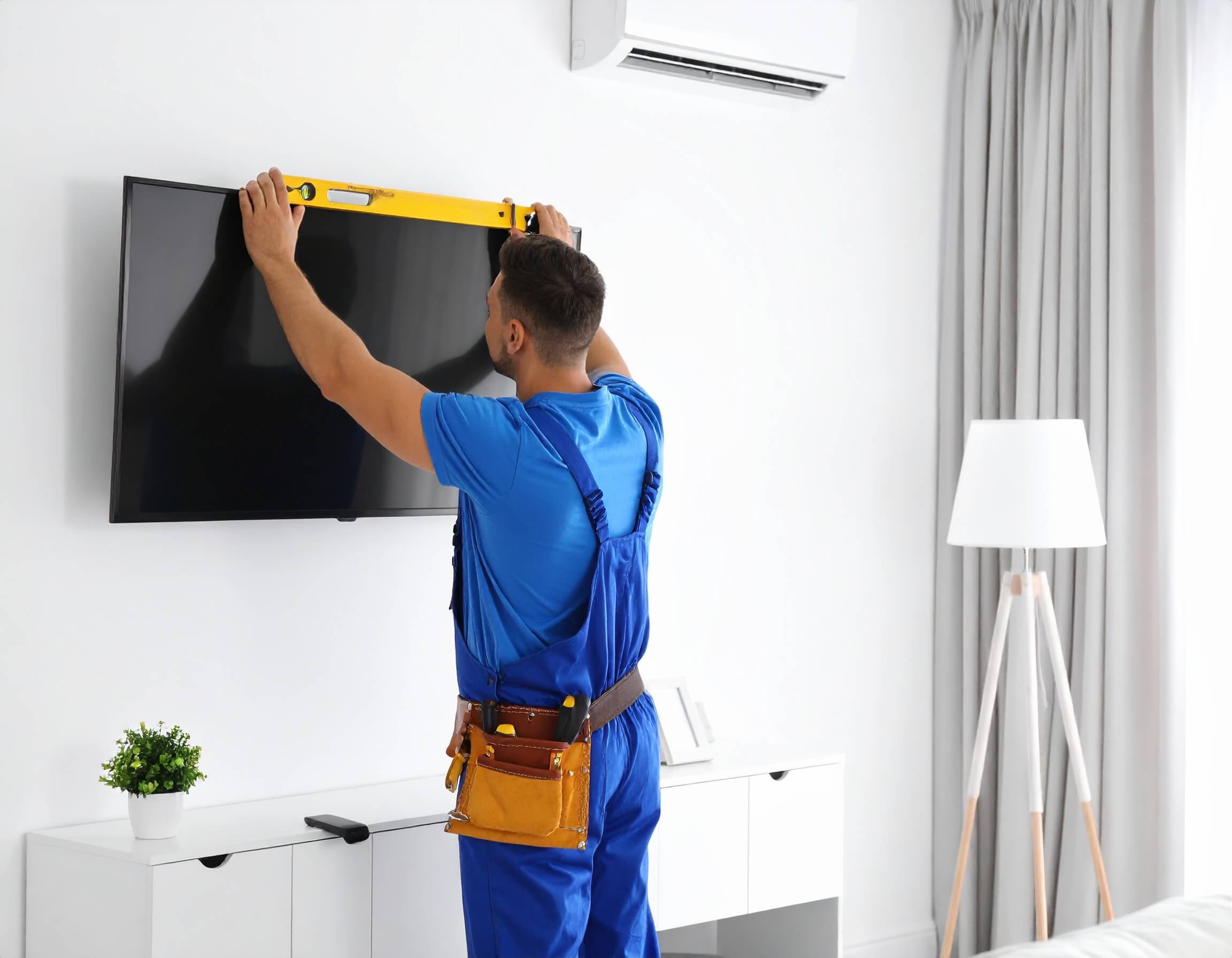 Handyman mounting a flat-screen TV with laser level